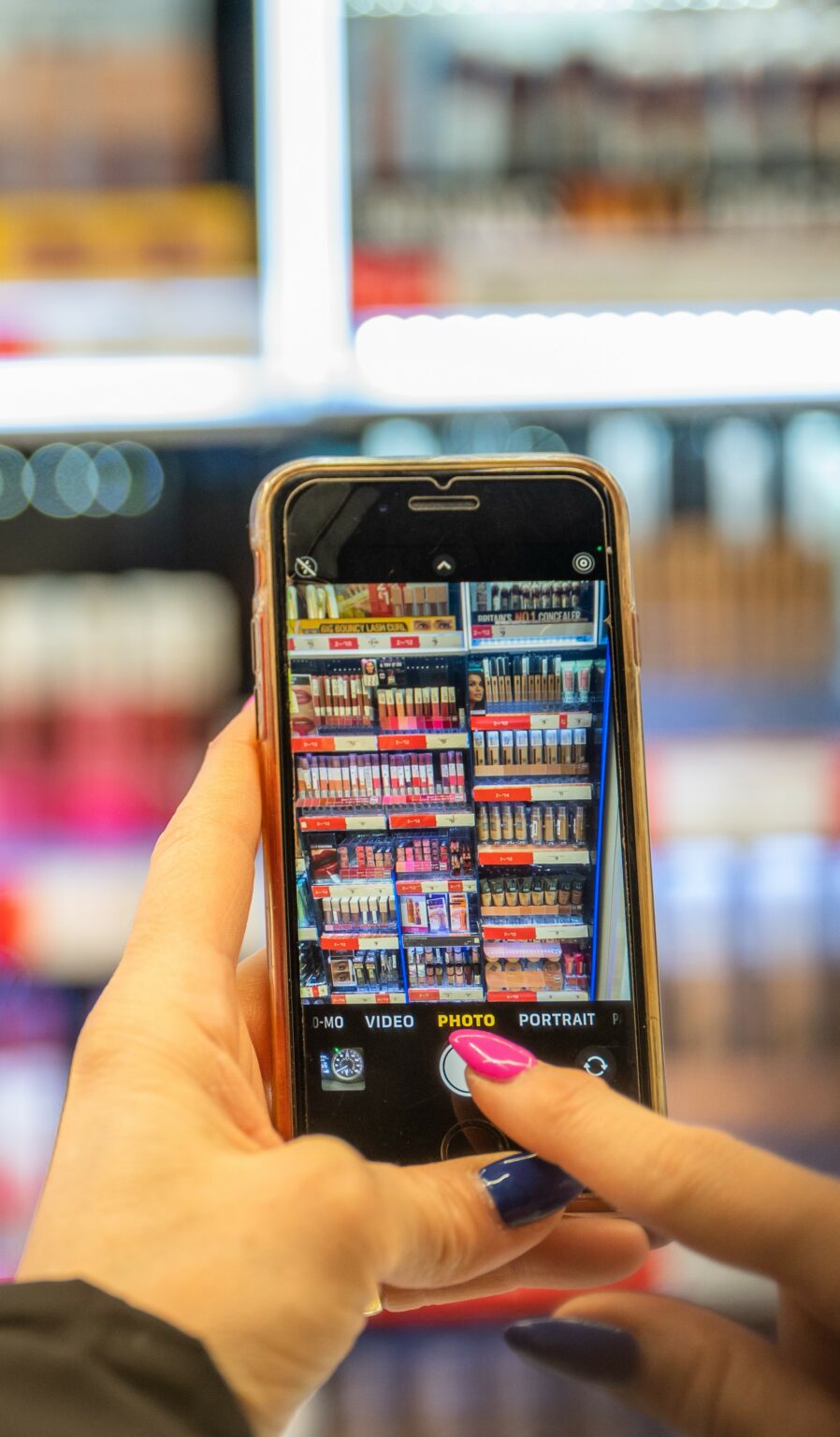 woman taking a picture of cosmetics in a store